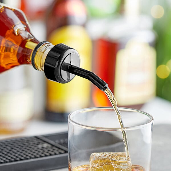 A Choice black free flow whiskey pourer attached to a bottle pouring liquid into a glass.