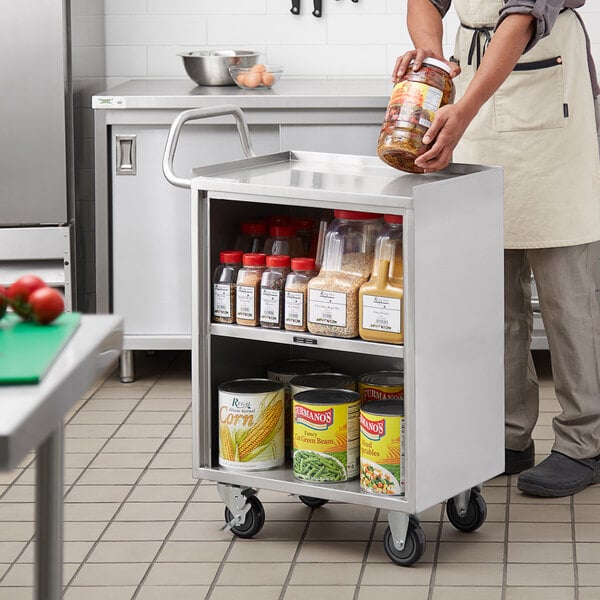 A man putting a jar of food on a Regency stainless steel utility cart.