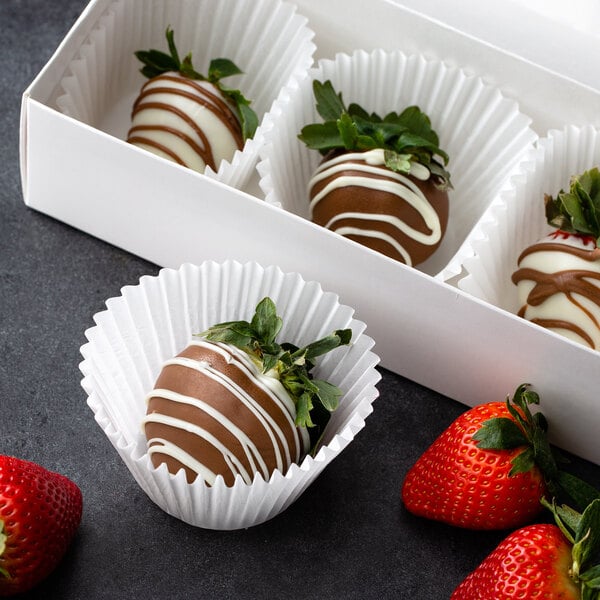 A chocolate covered strawberry in a white fluted paper wrapper.