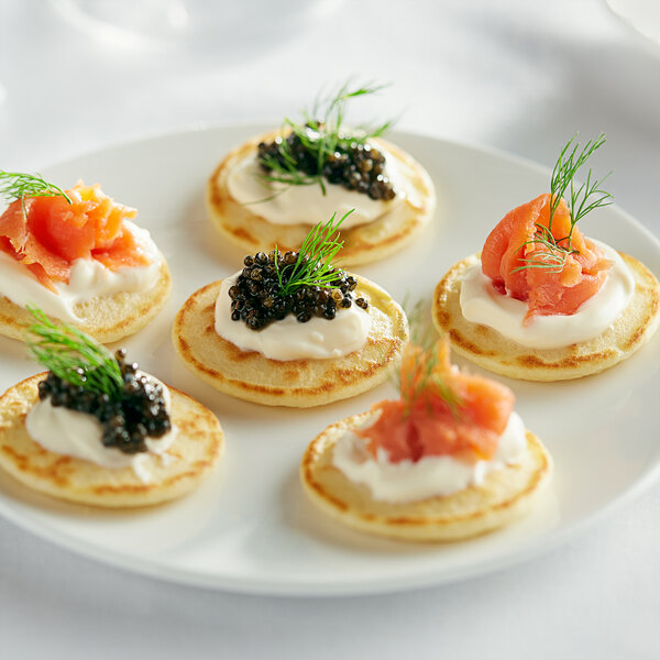 A plate topped with White Toque mini blini with salmon and caviar.