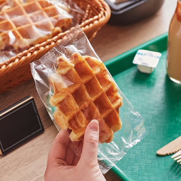 A hand holding a White Toque Liege waffle in a plastic bag.