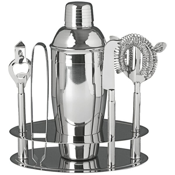 A Franmara silver cocktail shaker with bar tools on a metal stand.