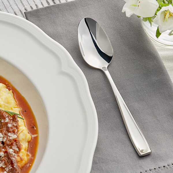 An Acopa Monte Bianco stainless steel spoon on a plate with food.