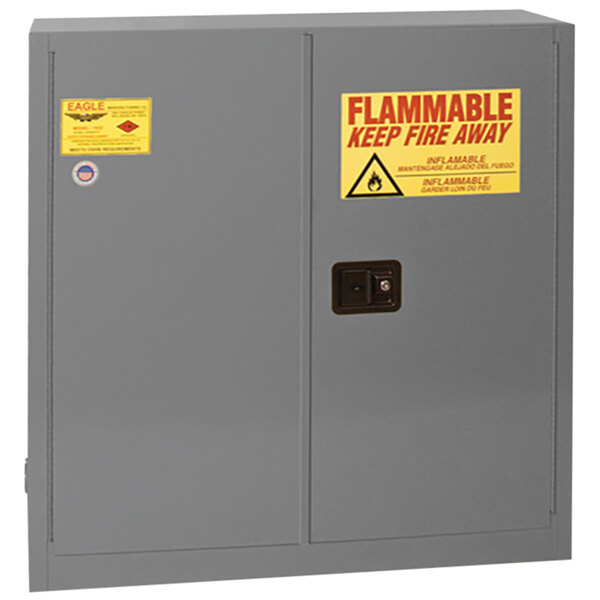 An Eagle Manufacturing grey safety cabinet with yellow and red flammable labels.