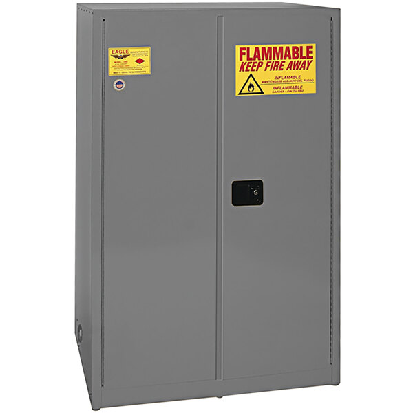 A gray metal Eagle flammable liquid safety cabinet with yellow and red warning labels.