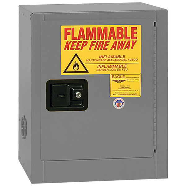 A grey Eagle Manufacturing safety cabinet with a yellow and red flammable liquid sign on the door.