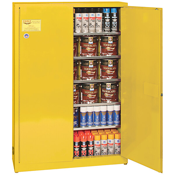 A yellow metal Eagle Manufacturing safety cabinet with cans of paint on the shelves.