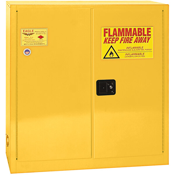 A yellow metal Eagle Manufacturing safety cabinet with a sign.
