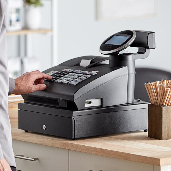 A person using a Royal Alpha cash register on a counter.