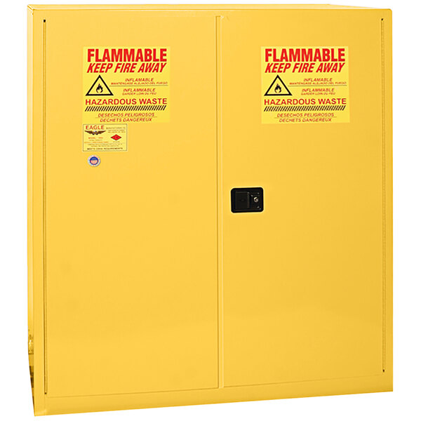 A yellow Eagle Manufacturing HazMat safety cabinet with 2 manual-closing doors and red and white signs.