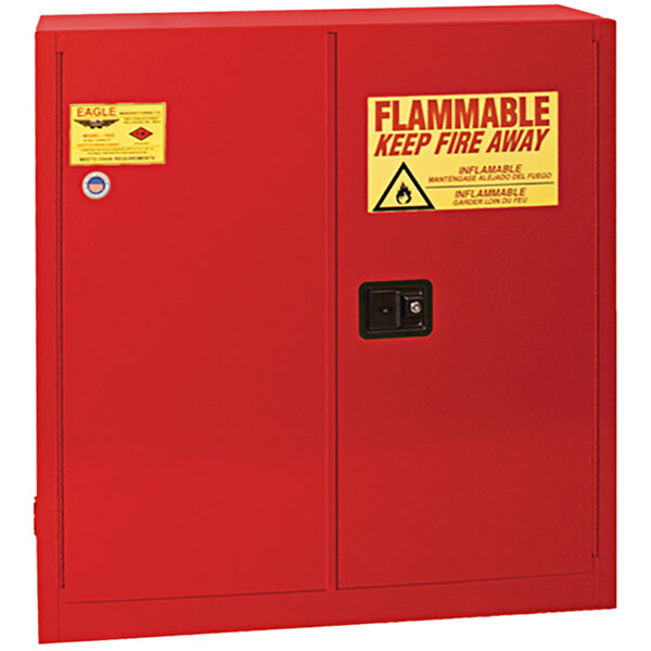 A red Eagle Manufacturing flammable liquid safety cabinet with a yellow and red warning sign.