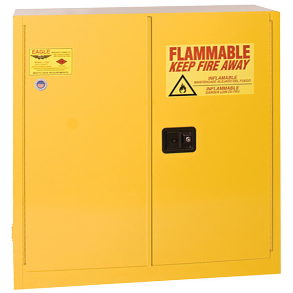 A yellow Eagle Manufacturing safety cabinet with a red and white warning sign for flammable liquids.