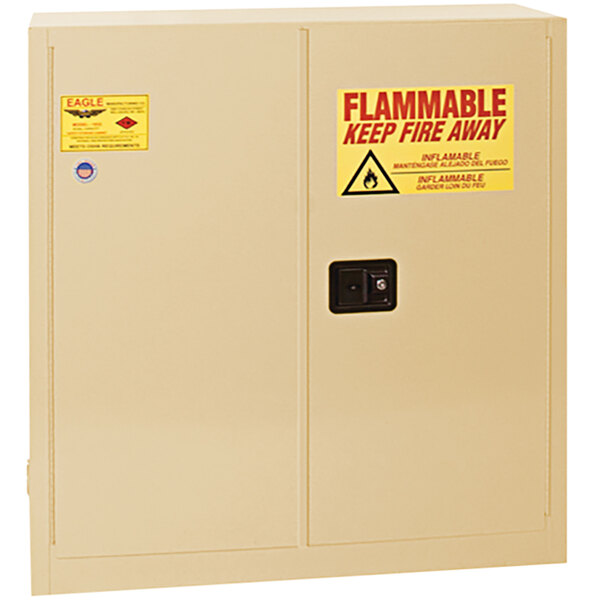 A beige Eagle Manufacturing flammable safety cabinet with a yellow and red warning sign.