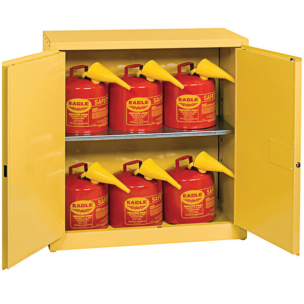 A yellow metal Eagle Manufacturing safety cabinet with red containers inside.