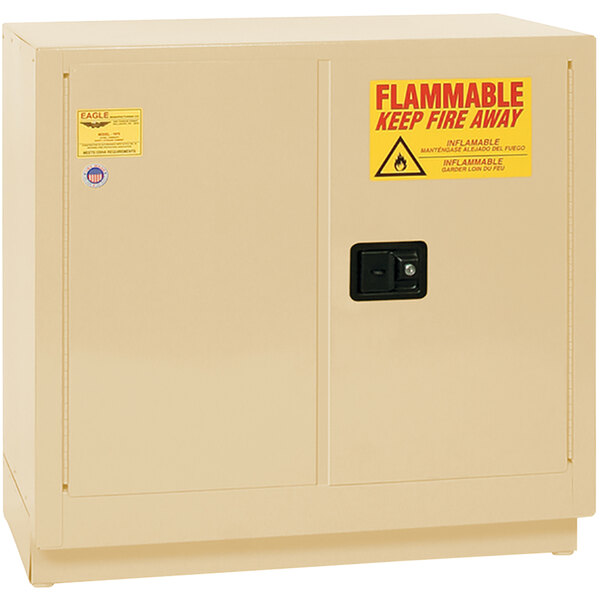 A tan metal Eagle safety cabinet with yellow and red flammable liquid safety signs.