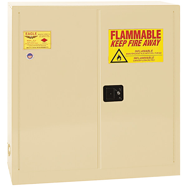 A beige Eagle Manufacturing flammable safety cabinet with a yellow sign reading "Flammable - Keep Fire Away" in red and black letters.