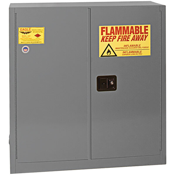 A grey Eagle Manufacturing safety cabinet with a yellow and red flammable label.