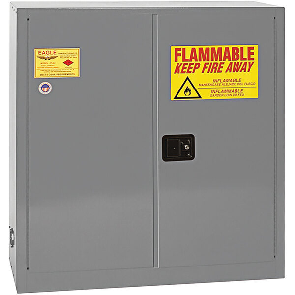 A grey Eagle Manufacturing safety cabinet with a yellow and red flammable label.