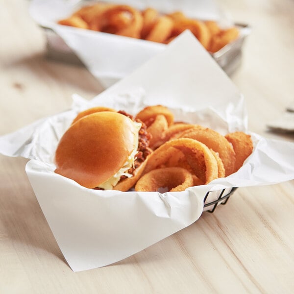 A white basket liner with a close-up of onion rings and burgers.