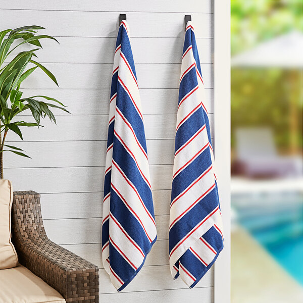 Two Monarch Brands navy blue and red striped pool towels hanging on a wall.