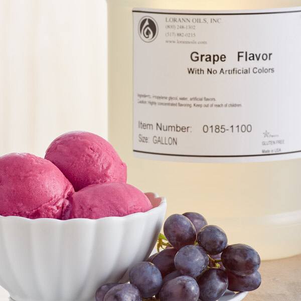 A bowl of pink ice cream and grapes next to a bottle of LorAnn Oils grape flavoring.