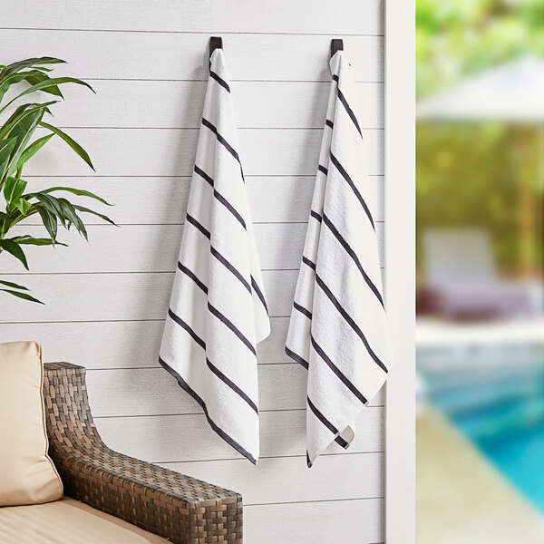 Two Monarch Brands dark gray striped pool towels hanging on a wall.