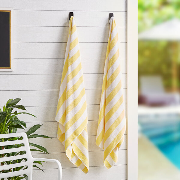 A yellow and white striped Monarch Brands pool towel hanging on a hook.