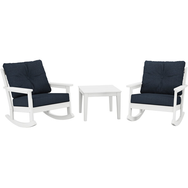 Two white POLYWOOD Vineyard rocking chairs with blue cushions at a white table.
