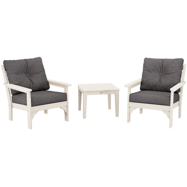 A white table with legs between two grey chairs with white cushions.