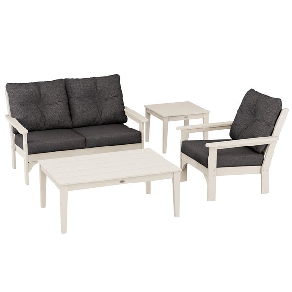 A white POLYWOOD patio set with black cushions including chairs, a bench, and tables.