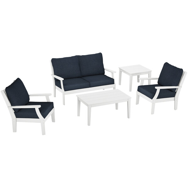 A white POLYWOOD patio set with blue cushions on a chair and a blue table next to a white table and chairs.