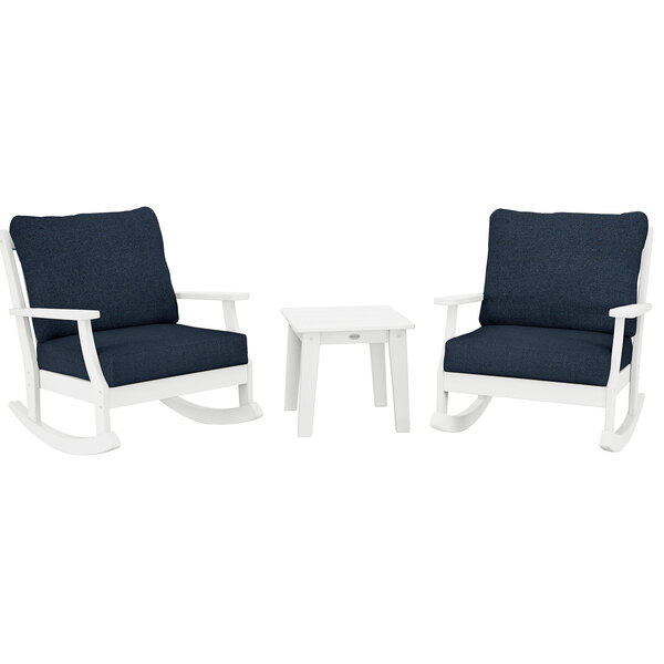 Two white POLYWOOD rocking chairs with blue cushions and a white table with legs.