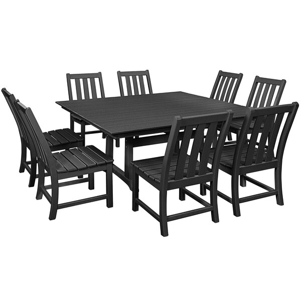 A POLYWOOD black farmhouse trestle dining table and chairs on an outdoor patio.