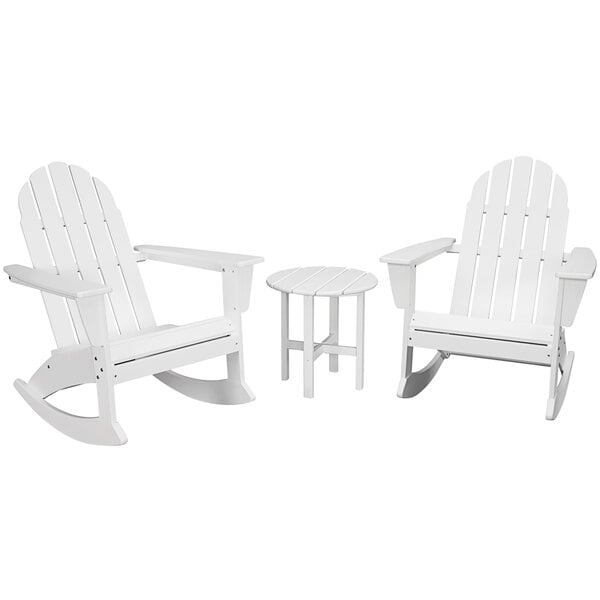 A group of white POLYWOOD Adirondack rocking chairs and a small round table.