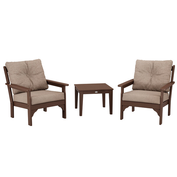 A POLYWOOD mahogany deep seating patio set with brown cushions on three chairs and a table.