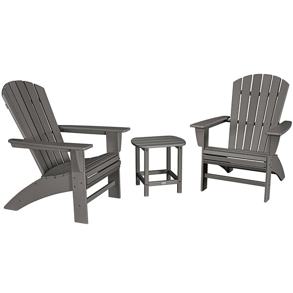 A group of three POLYWOOD slate grey Curveback Adirondack chairs and a table set on an outdoor patio.