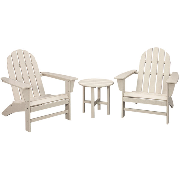 A round white table with legs and three white Adirondack chairs with armrests.