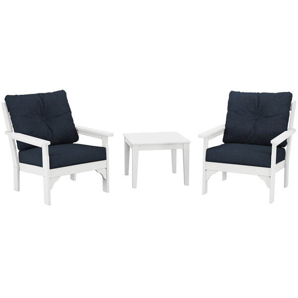A white POLYWOOD table with legs and two white chairs with blue cushions.