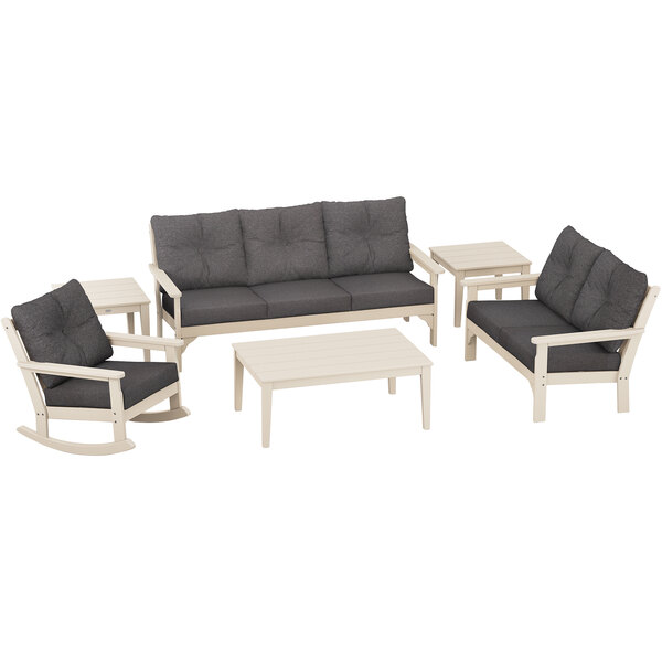 A grey POLYWOOD outdoor seating set with a white table and black cushions.