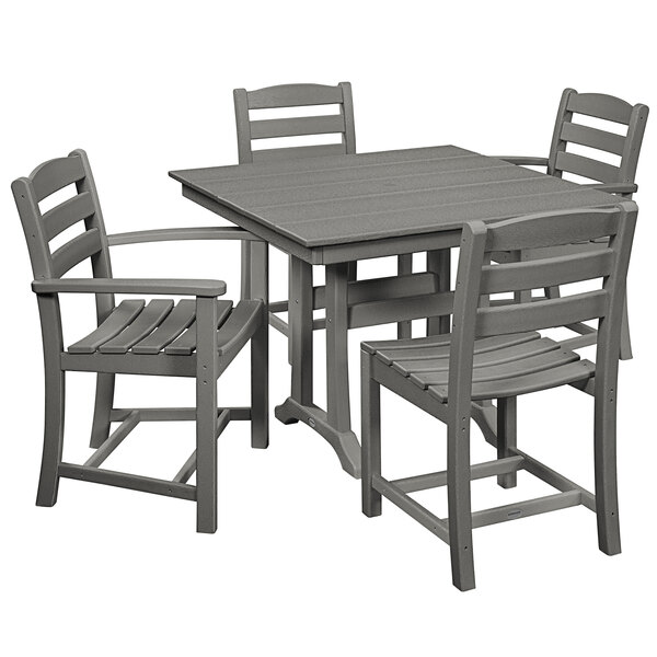 A POLYWOOD La Casa Cafe farmhouse dining table in slate grey with four chairs on an outdoor patio.