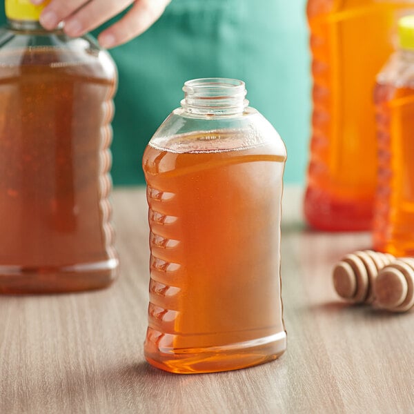 A person holding a ribbed hourglass bottle of honey.