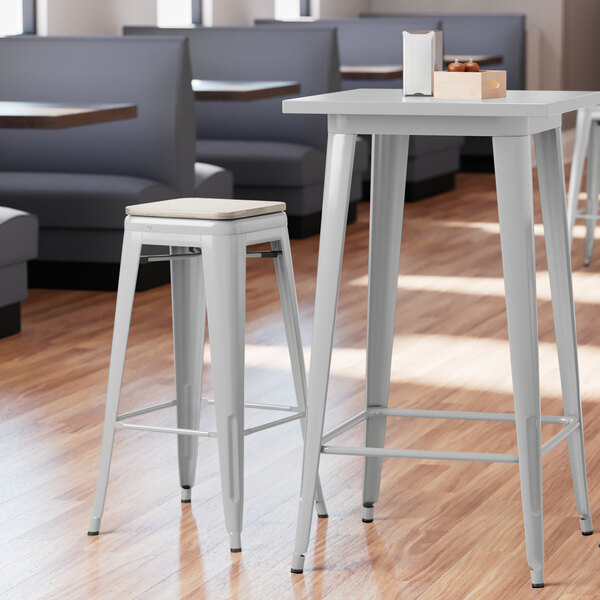 A Lancaster Table & Seating backless barstool with a gray wood seat at a table in a restaurant.