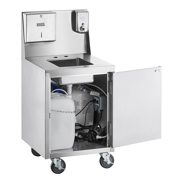 A stainless steel portable hand sink cart with a single bowl, paper towel dispenser, soap dispenser, and an open cabinet door revealing water tanks and plumbing components inside.