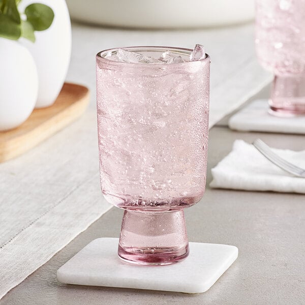 An Acopa mauve goblet filled with water on a white coaster.