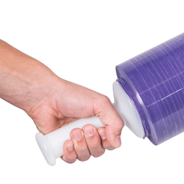 A hand using a white plastic handle to dispense purple pallet wrap.