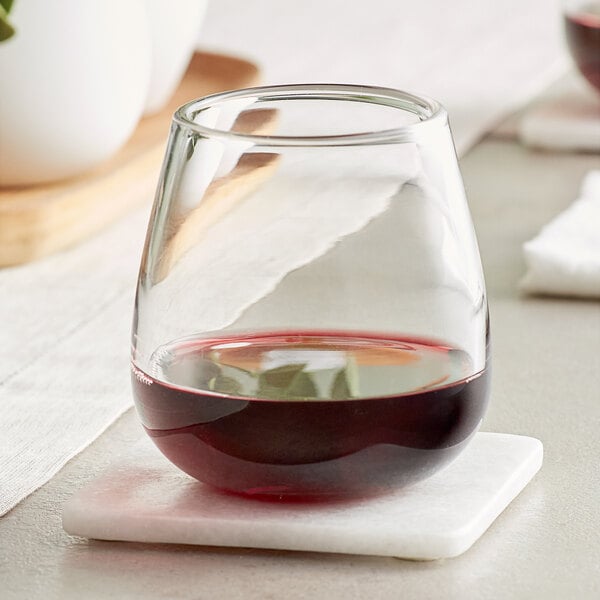 An Acopa Pangea stemless wine glass filled with red wine on a marble coaster.