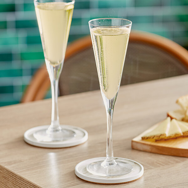 Two Acopa Select Trumpet flute glasses of champagne on a table.