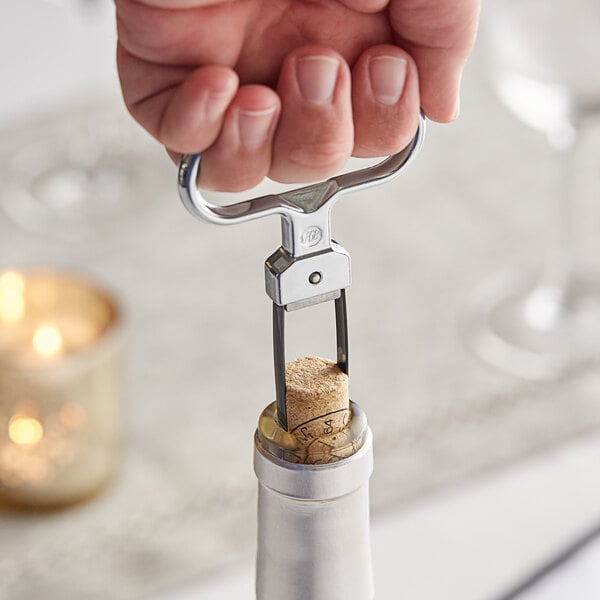 A hand using a Vacu Vin 2-prong wine cork extractor to open a cork at a fine dining restaurant.