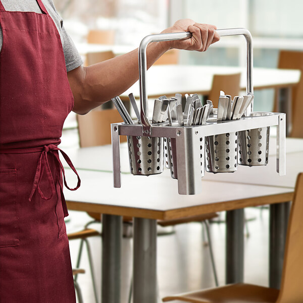 A man holding a Choice stainless steel flatware carrier full of utensils.
