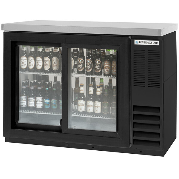 A black Beverage-Air back bar refrigerator with sliding glass doors filled with beer bottles.